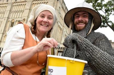People dressed in historic clothing holding a donations bucket